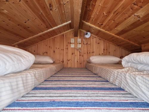 two beds in a room with wooden walls at Cozy cottage on beautiful Rossö, Orust SE09130 in Röd