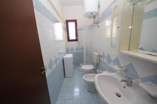 een badkamer met 2 toiletten, een wastafel en een spiegel bij Bright flat in Rosolina with shared pool in Rosolina Mare