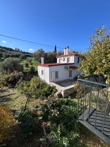 a small white house in the middle of a field at Δωμάτια Εξοχή-With fireplace and view to the sea in Elíki