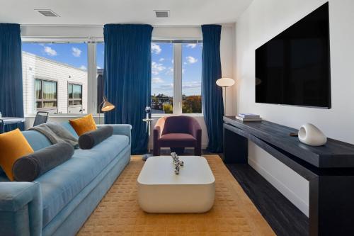a living room with a blue couch and a tv at Hyatus Luxury Residences Boston South Bay Designer Collection in Boston