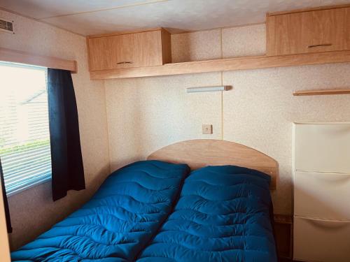 a bedroom with a blue bed in a caravan at Camping de Zandput - ZP 340 in Vrouwenpolder