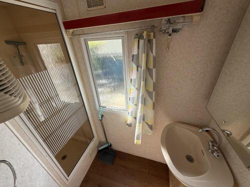 a bathroom with a sink and a shower and a window at Camping de Zandput - ZP 340 in Vrouwenpolder