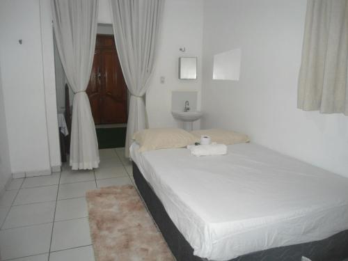 een kleine slaapkamer met een bed en een wastafel bij Kit Net, No Centro Comercial de Belém in Belém