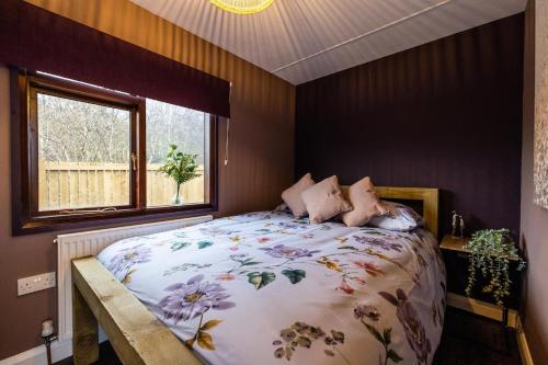 a bedroom with a large bed and a window at The Woodland Lodge - Wood Fired Hot Tub and Firepit in Hambleton