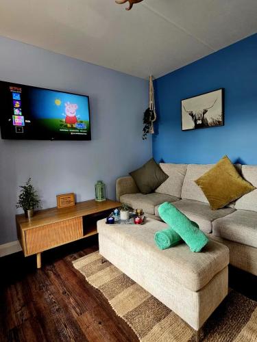 a living room with a couch and a flat screen tv at The Woodland Lodge - Wood Fired Hot Tub and Firepit in Hambleton