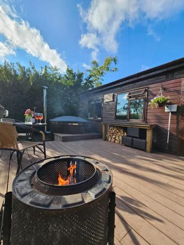 a fire pit on a deck with a house at The Woodland Lodge - Wood Fired Hot Tub and Firepit in Hambleton