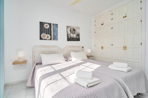 a white bedroom with a bed with two towels on it at Apto 5 Almoraide Suites in Nerja