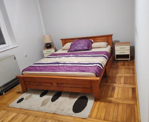 een slaapkamer met een bed met een paars kussen en een vloerkleed bij Signorina in Sajmište