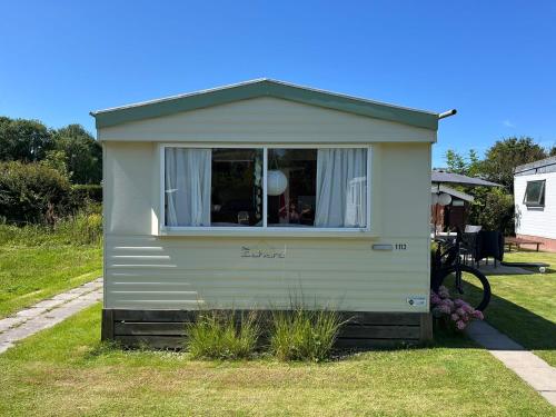 ein weißer Anhänger mit einem Fenster in einem Hof in der Unterkunft Beach Resort Kamperland - 1113 in Wissenkerke