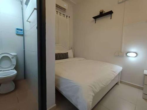 een kleine slaapkamer met een bed en een toilet bij Melaka Kota Home in Melaka
