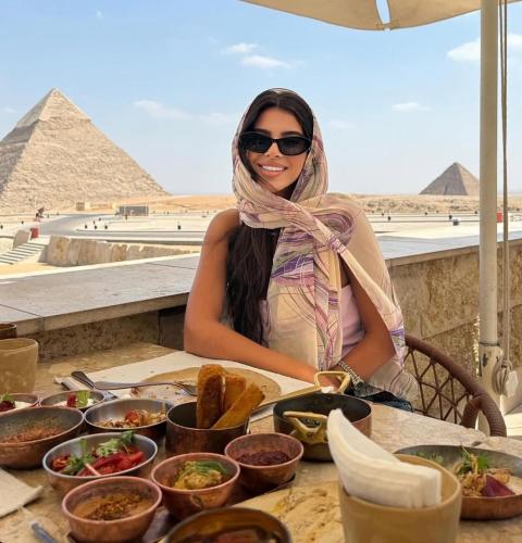 a woman sitting at a table with food in front of the pyramids at Fanton Hotel in Cairo