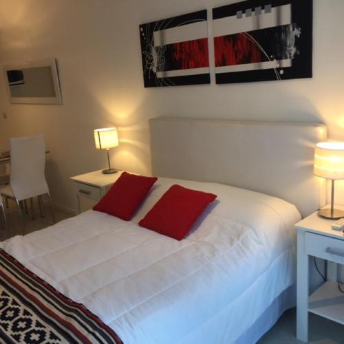 1 dormitorio con 1 cama blanca y 2 almohadas rojas en Casa ivana 3 en Buenos Aires