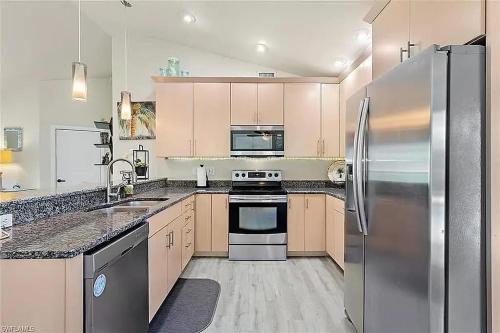 a kitchen with a stainless steel refrigerator and cabinets at Summer Getaway (Gulf-access retreat) in Cape Coral