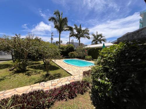 a swimming pool in a yard with palm trees at Pepa Kingdom in Matinhos