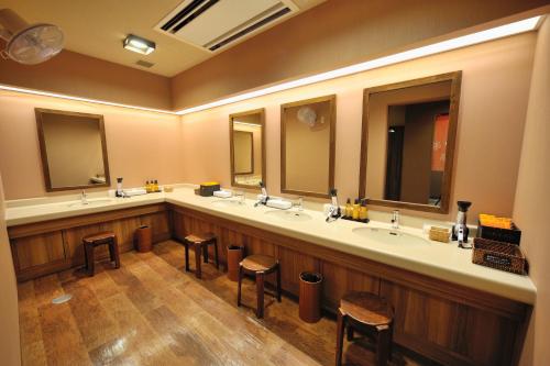 a large bathroom with three sinks and two stools at Dormy Inn Express Koriyama in Koriyama