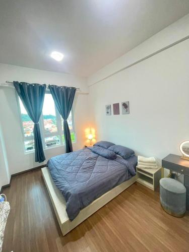 een slaapkamer met een bed met blauwe lakens en een bureau bij Jhomestay1 in Sandakan