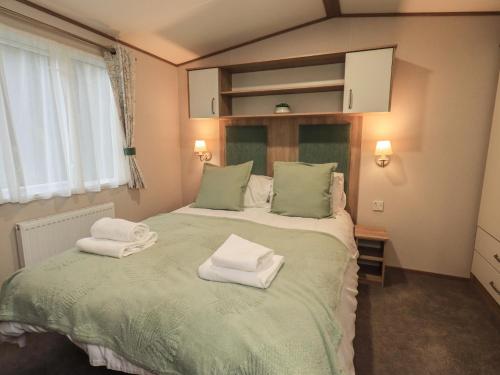 a bedroom with a bed with towels on it at Foxwood Hideaway in Carnforth