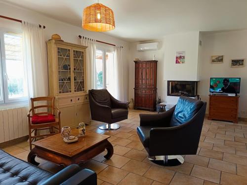 Una sala de estar con un sofá y sillas y una mesa. en Face à la Citadelle - Jardin & Parking privé, en Forcalquier