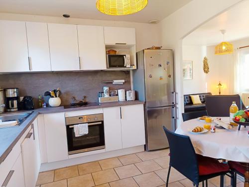 Una cocina con gabinetes blancos y una mesa con un mantel blanco. en Face à la Citadelle - Jardin & Parking privé, en Forcalquier