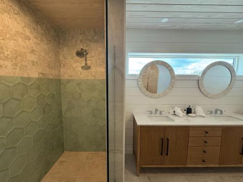a bathroom with a sink and two mirrors at Kalopsia Seaside Villas & Marina in Great Guana Cay