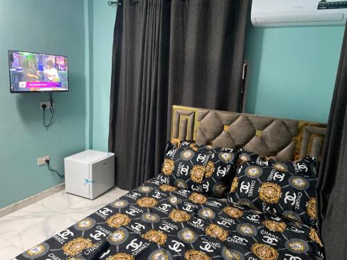 a bedroom with a bed with pillows and a tv at Prof's Villa in Kumasi