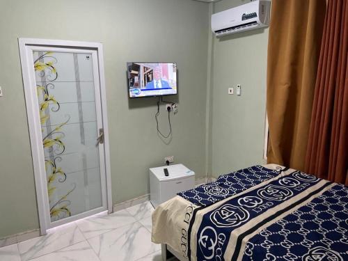 a bedroom with a bed and a tv on the wall at Prof's Villa in Kumasi