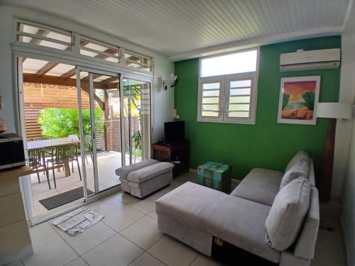 a living room with a couch and a green wall at Superbe T3 avec une grande terrasse et un accès direct aux 2 plages Gros Raisin in Sainte-Luce