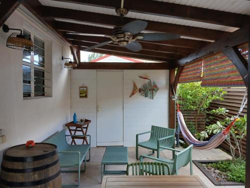 a patio with chairs and a ceiling fan and a hammock at Superbe T3 avec une grande terrasse et un accès direct aux 2 plages Gros Raisin in Sainte-Luce