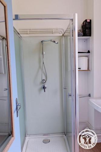 a shower with a glass door in a bathroom at Gîte ecole 3 in Soursac