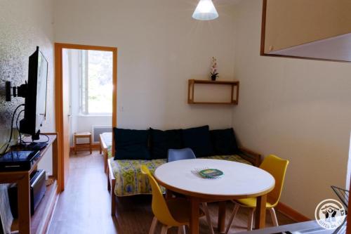 una sala de estar con una mesa y un sofá en Gite ecole, en Soursac