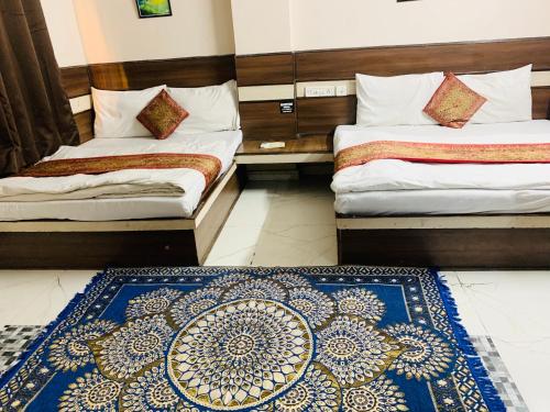 two beds in a room with a blue rug at Hotel Churu Palace in Jaipur