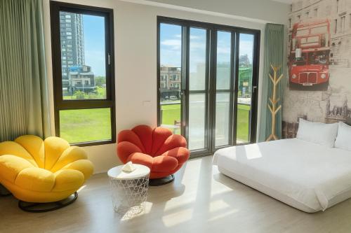 a bedroom with two chairs and a bed and windows at Blue Sea and Sunny B&B in Toucheng