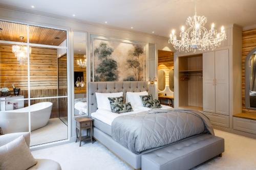 a bedroom with a tub and a bed and a chandelier at Skýra Retreat in Rovaniemi