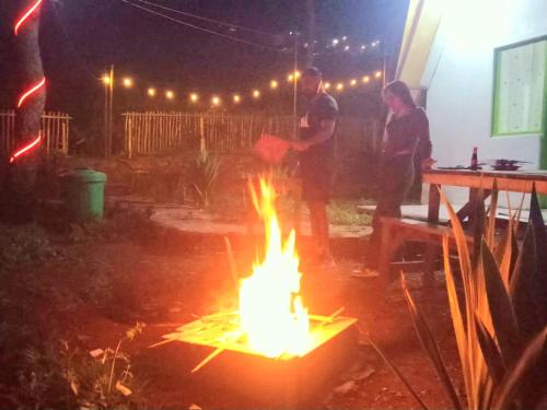 two men standing around a fire in a yard at night at Aubrey Villa Ciwidey in Pengalengan