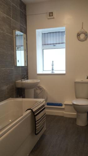 ein Badezimmer mit einer Badewanne, einem Waschbecken und einem WC in der Unterkunft 17 The Green Holiday Apartment in Tenby