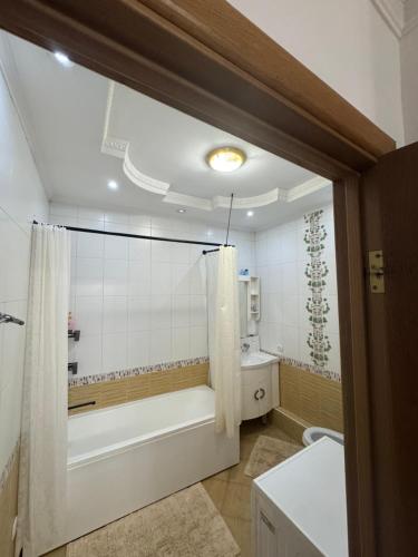 a bathroom with a tub and a toilet and a shower at spacious apartment in Almaty