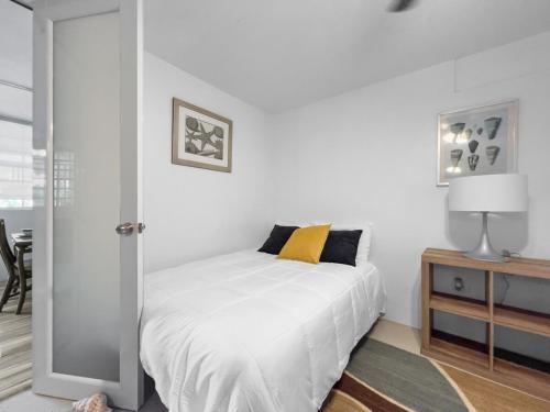 Dormitorio blanco con cama con almohada amarilla en Tropical Naguabo Beach House Pool n Beach, en Naguabo