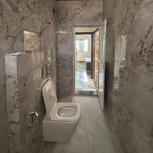 uma casa de banho com um WC numa parede de pedra em Nomadic Patna em Patna