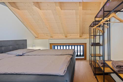 Un dormitorio con una cama y un techo de madera. en Visionary Hospitality Bassersdorf, Zürich - Premium Apartments in Swiss Style with Free Parking, Washer, Kitchen, Terrace, Vaulted Cellar Event Room, Bus Stop, 15' City & Airport, en Bassersdorf