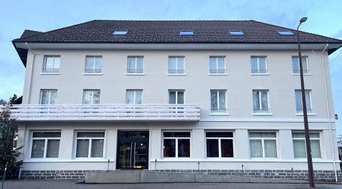 Un edificio blanco con un balcón en la parte superior. en Hôtel La Réserve, en Gérardmer