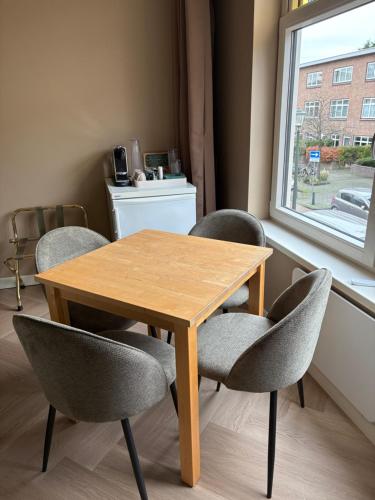 a wooden table and chairs in a room with a window at Morelstraat in The Hague