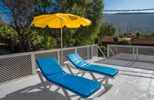 Elegant Family Chalet a Imi Ouaddar Comfort & Calm في أغادير: كرسيان أزرقان ومظلة صفراء في فناء