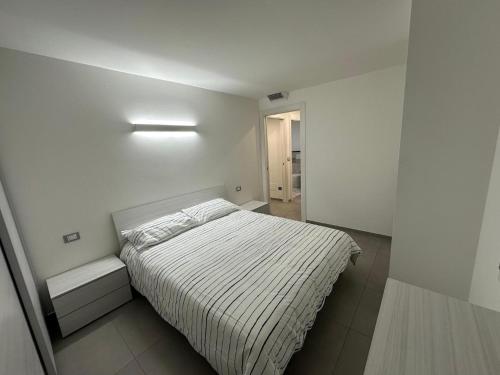 a white bedroom with a bed and a light at Sea House Superior in Pietra Ligure