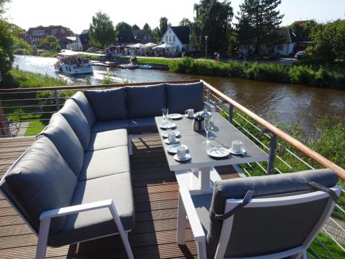 een tafel en stoelen op een terras naast een rivier bij Ferienwohnung Harlezauber Carolinensiel in Carolinensiel