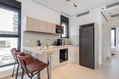 Una cocina con una encimera con sillas y un refrigerador. en Melony Apartments Htmarim 22 Street, en Eilat