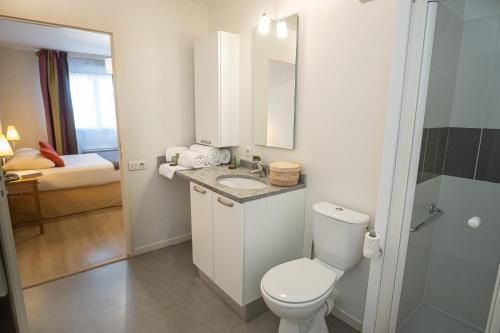 a bathroom with a toilet and a sink with a mirror at Domitys Les Châtaigniers in Panazol