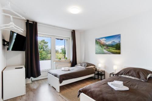 ein Schlafzimmer mit zwei Betten und einem Fernseher und einem Fenster in der Unterkunft Schöne Wohnung in Geseke in Niederdorla