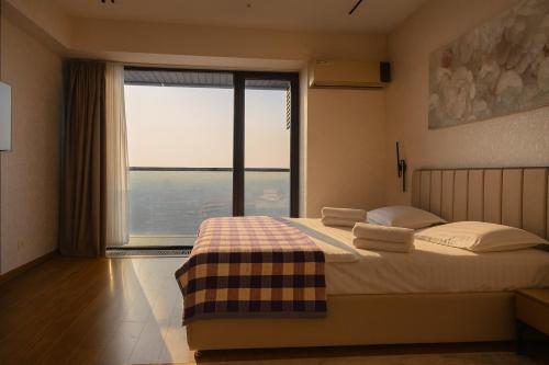 ein Schlafzimmer mit einem Bett mit einem großen Fenster in der Unterkunft U-tower 18 apartment in Chilanzar