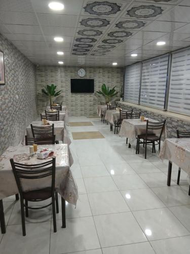 een restaurant met tafels en stoelen en een flatscreen-tv bij Kahraman Amman Hotel in Amman