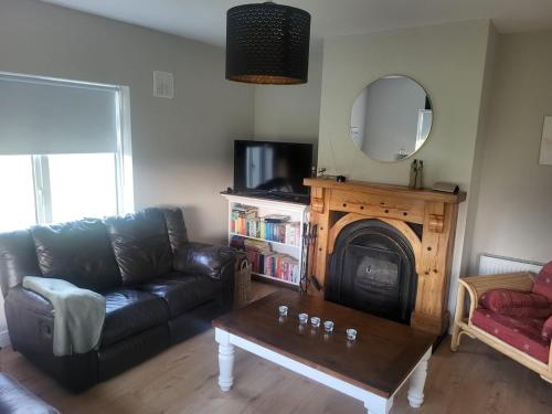 a living room with a black couch and a mirror at Sunny south east in Wexford in Blackwater